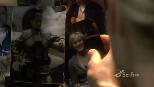 Una mano sostiene fotos de los caídos en la pared conmemorativa del Galactica
