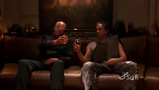 Saul Tigh y Galen Tyrol bebiendo sentados en un sofá en Battlestar Galactica