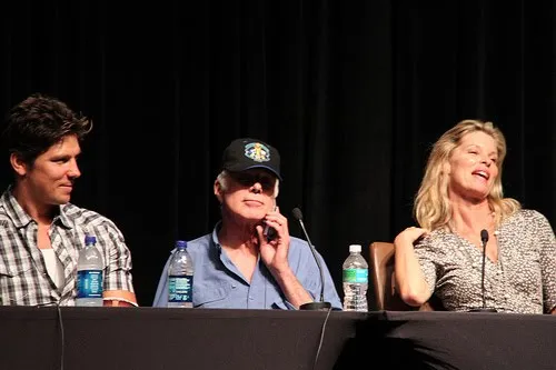 Michael Trucco, Michael Hogan y Kate Vernon sentados en el panel, ella riendo