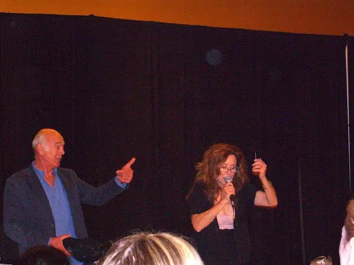 Michael Hogan y Mary McDonnell bromeando de pie en el escenario de la Dragon Con