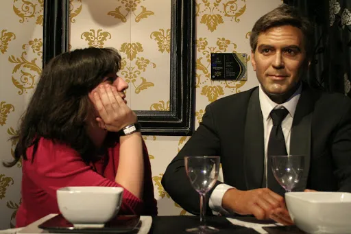 Dids sentada a la mesa con la figura de cera de George Clooney en Madame Tussauds