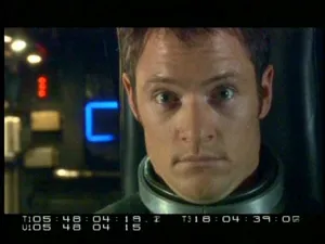 Un piloto con el traje de vuelo mirando a cámara en el gag reel de Battlestar Galactica