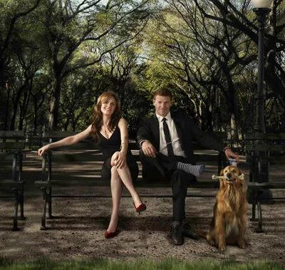 Brennan y Booth sentados en un banco del parque con un perro en Bones