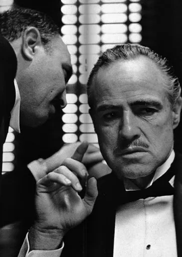 Marlon Brando como Vito Corleone escuchando un susurro en El padrino