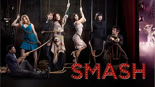 El reparto de Smash posando entre cuerdas de tramoya en un teatro