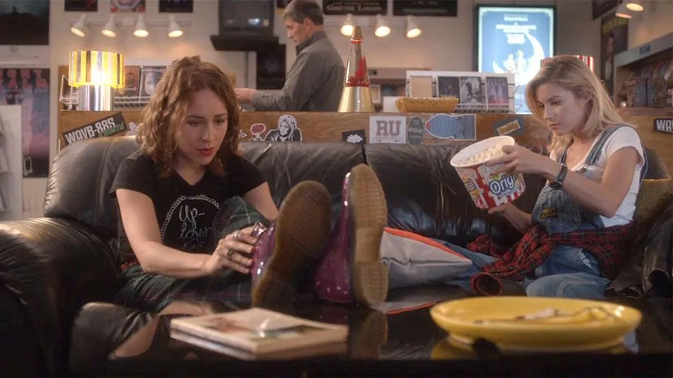 Dos amigas en un sofá de un videoclub de los noventa en Hindsight