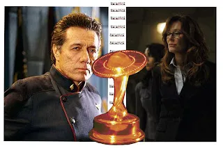 Adama y Roslin junto a un premio Saturn